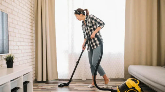 Woman using a central vacuum system to clean hardwood floor in a modern living room